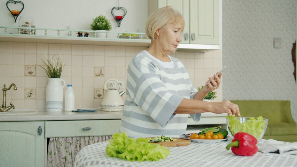 Mujer mayor preparando una ensalada en su cocina